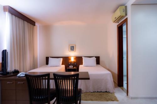 a hotel room with two beds and a table and chairs at Hotel Santos Dumont in Goiânia