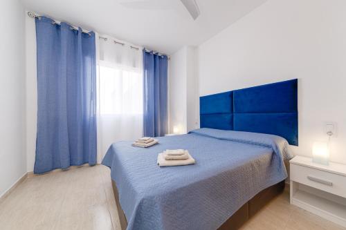 1 dormitorio con 1 cama azul y 2 toallas en Casa Godisa, en Torrevieja