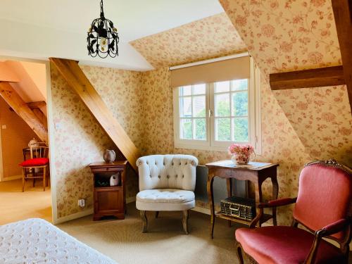 ein Schlafzimmer mit einem Stuhl, einem Tisch und einem Fenster in der Unterkunft Les Forrières Maison de Campagne in Thil-Manneville