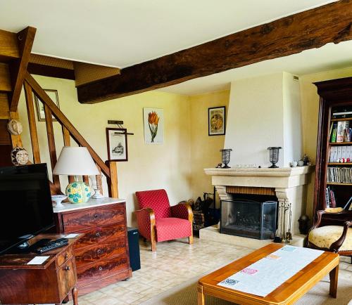 ein Wohnzimmer mit einem Kamin und einem roten Stuhl in der Unterkunft Les Forrières Maison de Campagne in Thil-Manneville