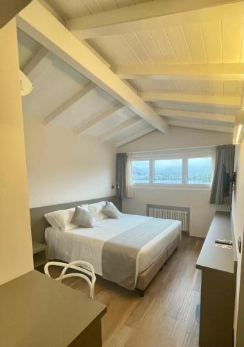 a bedroom with a large bed in a room with windows at Hotel Baia di Paré in Valmadrera