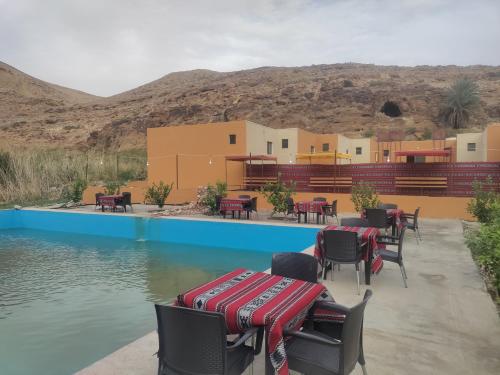 a patio with tables and chairs next to a pool at Sail Alhasa Tourist Resort-Tafila in At-Tafilah