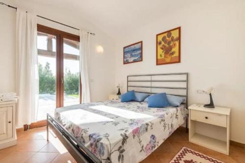 sypialnia z łóżkiem z niebieskimi poduszkami i oknem w obiekcie Villa Babajola - 500m from the beach w mieście Costa Rei