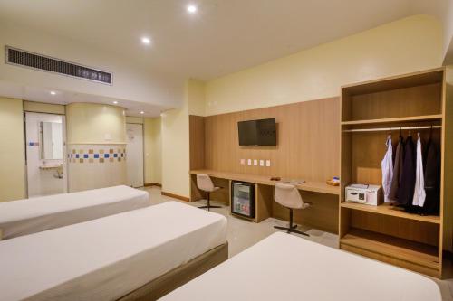 a hotel room with two beds and a desk at Rio Aeroporto Hotel Galeão in Rio de Janeiro