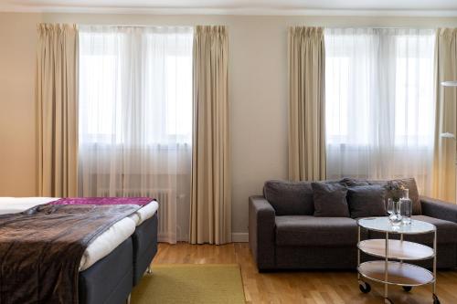 a bedroom with a bed and a couch and a chair at Elite Stadshotellet Växjö in Växjö