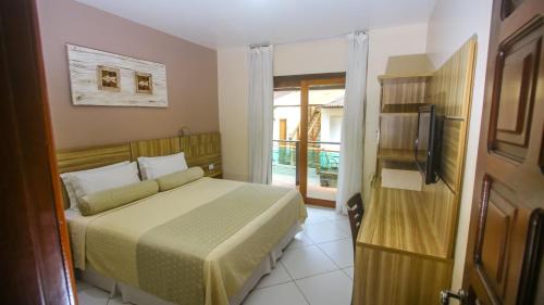 a bedroom with a bed and a television in a room at Pousada Safira do Morro in Morro de São Paulo