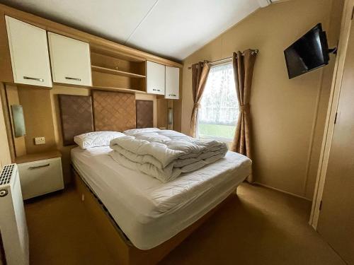 Cama pequeña en habitación con ventana en Lovely 6 Berth Caravan With Wifi At Steeple Bay In Essex Ref 36028b, en Southminster