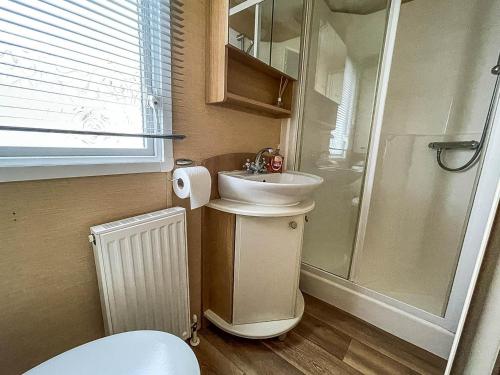 a small bathroom with a sink and a shower at Lovely 6 Berth Caravan With Wifi At Steeple Bay In Essex Ref 36028b in Southminster