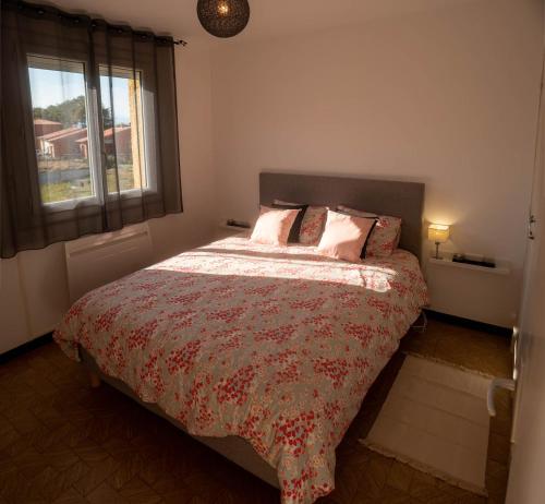 a bedroom with a bed with a red comforter and a window at Entre Monts et Vermeille in Sorède