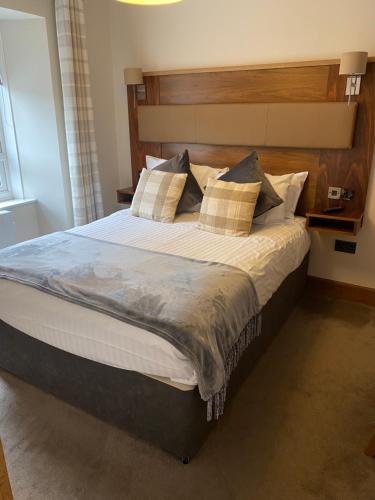a bedroom with a large bed with a wooden headboard at Garden Rooms in Pitlochry