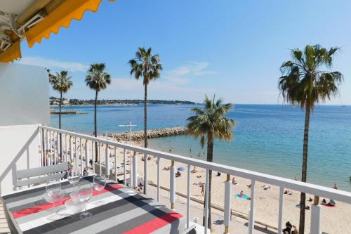 a balcony with a view of the beach and palm trees at Splendid T2 "San Remo" waterfront air-conditioned and with parking in Juan-les-Pins
