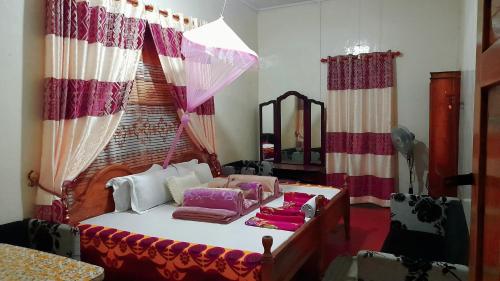 1 dormitorio con 1 cama con cortinas y espejo en Bel View Guest House, en Haputale