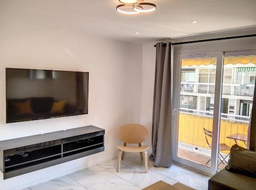 a living room with a flat screen tv and a chair at Résidence le Serra A2 in Juan-les-Pins