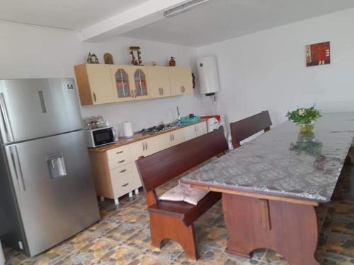 a kitchen with a table and a stainless steel refrigerator at Casa EliAndrei in 2 Mai