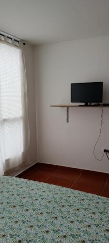 a bedroom with a tv on a white wall at Dulce hogar baño compartido in Chía
