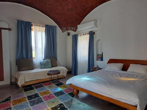The Roof by Barefoot in Tunis في Tunis: غرفة نوم بسريرين واريكة وستائر زرقاء