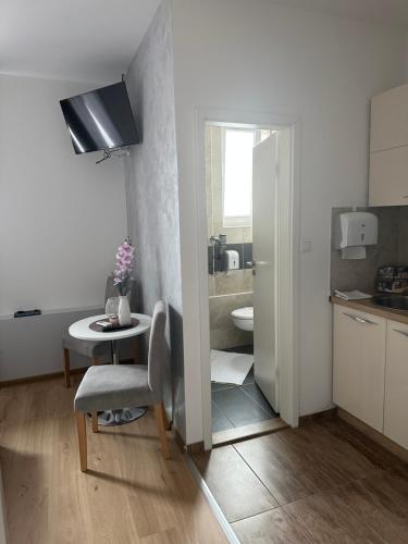 a small white kitchen with a table and a bathroom at San Lux Dunavska in Novi Sad