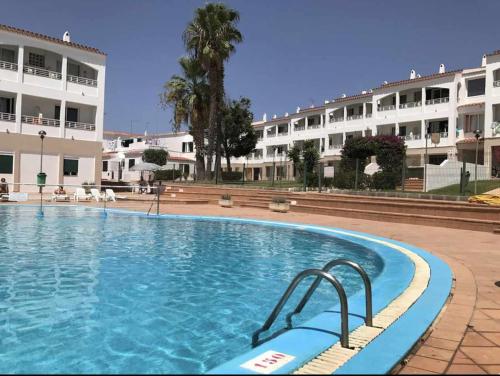 Apartamento bajo con piscina "Macarella" في كالا إن بلانيس: حمام سباحة كبير أمام مبنى