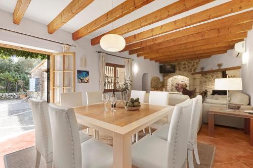 a dining room with a wooden table and white chairs at Villa Alyvos Pollensa - BY EMERALD STAY in Pollença