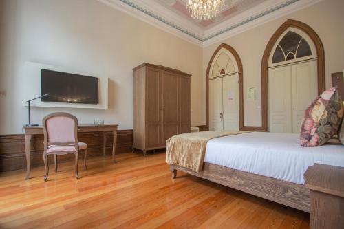 a bedroom with a bed and a desk and a tv at Dom José Alojamentos by Guestify in Guimarães