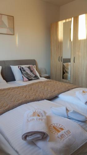 two beds in a hotel room with towels on them at San Lux Dunavska in Novi Sad