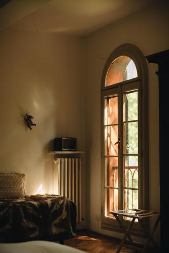 a bedroom with a large window and a bed and a radiator at Le dimore de Il borgo del balsamico in Albinea