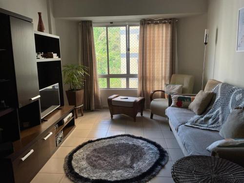 uma sala de estar com um sofá e uma televisão em Apartamento Guarujá Pitangueiras 50 metros Praia/3 Dormitórios/Vista do Mar, Sol da manhã no Guarujá
