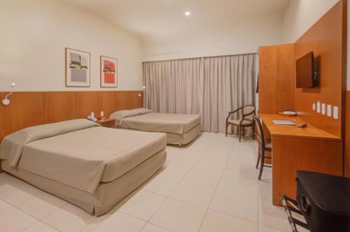 a hotel room with two beds and a desk at Rio Aeroporto Hotel Galeão in Rio de Janeiro