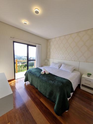 a bedroom with a large bed with a large window at Casa Primavera by The Lodges in Campos do Jordão