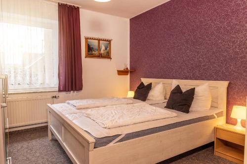 een slaapkamer met een groot bed met paarse muren bij 50095... in Carolinensiel