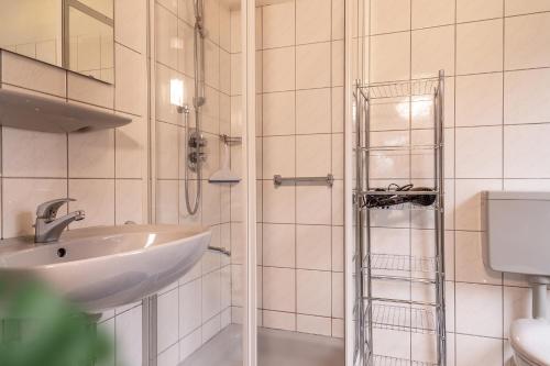 een witte badkamer met een wastafel en een douche bij 50095... in Carolinensiel