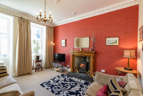 a living room with red walls and a fireplace at Horsemarket Apartment in Kelso