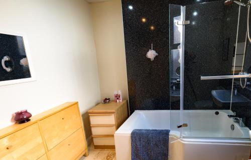 a bathroom with a tub and a glass shower at Horsemarket Apartment in Kelso