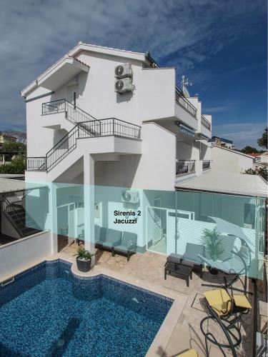a white building with a swimming pool in front of it at Villa Sirenis in Trogir