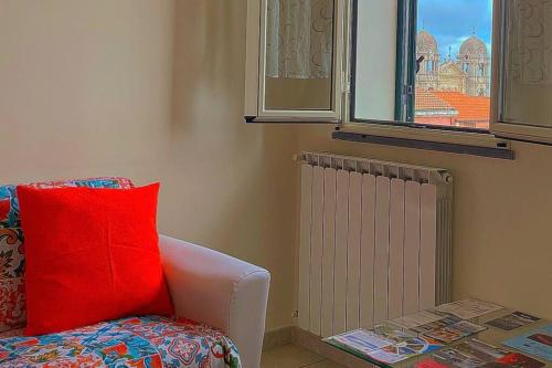 uma sala de estar com uma almofada vermelha e uma janela em Zafferana Apartment em Zafferana Etnea