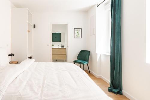 a bedroom with a white bed and a green chair at Calme & Chic vert - Proche gare et centre in Dijon