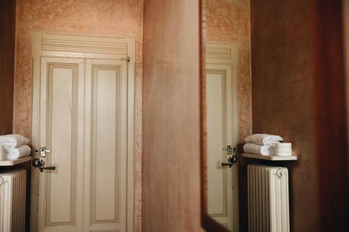 a bathroom with a door and a mirror and towels at Le dimore de Il borgo del balsamico in Albinea