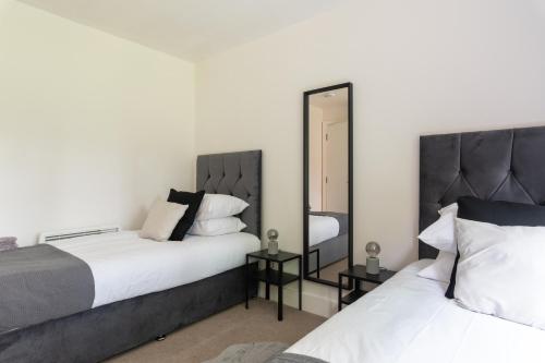 克勞利的住宿－Spacious, Modern, Fully Furnished Apartment - 2 FREE PARKING Spaces - 8 min LGW Airport，一间卧室配有两张床和镜子