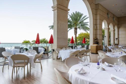 a restaurant with white tables and chairs and the ocean at Acqualina Resort and Residences in Miami Beach