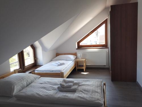 - une chambre mansardée avec 2 lits et une fenêtre dans l'établissement Apartmány Adam, à Liptovská Teplá
