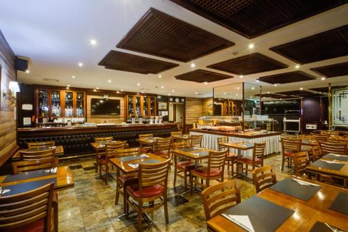 a restaurant with wooden tables and chairs and a bar at Rio Aeroporto Hotel Galeão in Rio de Janeiro