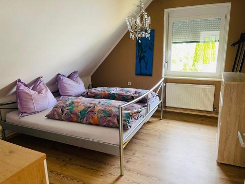 a bedroom with a bed with purple pillows and a chandelier at APARTMENT Schlossbergblick in Griffen