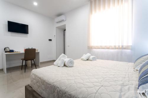 a white bedroom with a large bed with white pillows at Napul'è B&B in Boscotrecase
