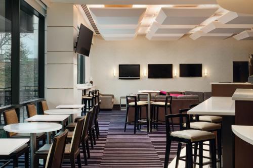 a dining room with tables and chairs and windows at Courtyard by Marriott New York JFK Airport in Queens