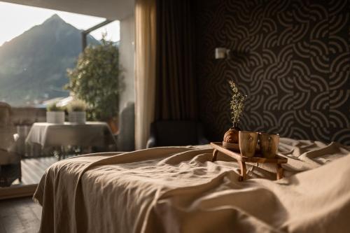 a bedroom with a bed with a table and a window at Landpalais Goyenhof - Deluxe Suites & Breakfast in Schenna