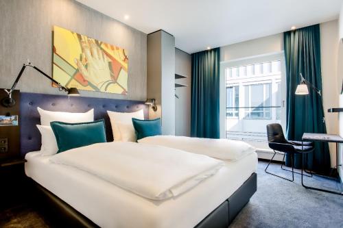 a hotel room with two beds and a desk at Motel One Mannheim in Mannheim