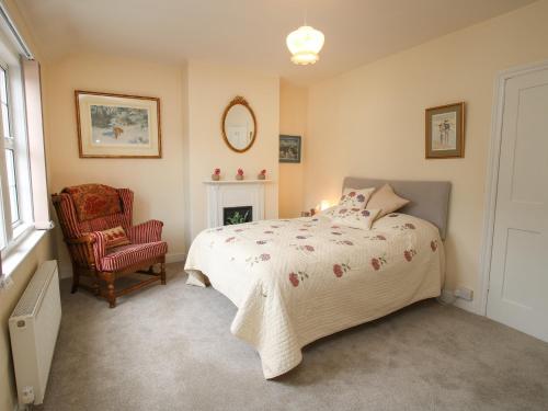 a bedroom with a bed and a chair at Penny Cottage in Ludlow