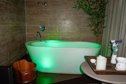 a green bath tub in a bathroom with a table at San Diego Suites Veredas Sete Lagoas in Sete Lagoas