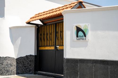 a black door to a white building with a sign on it at Napul'è B&B in Boscotrecase