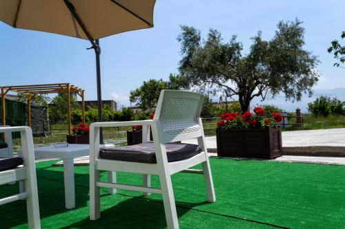 a white chair and an umbrella on a lawn at Napul'è B&B in Boscotrecase